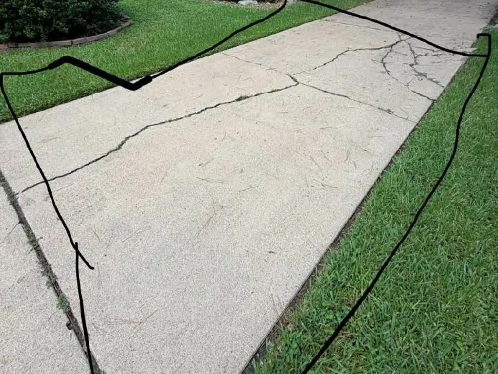 Cracked concrete driveway marked for replacement by Quality Construction