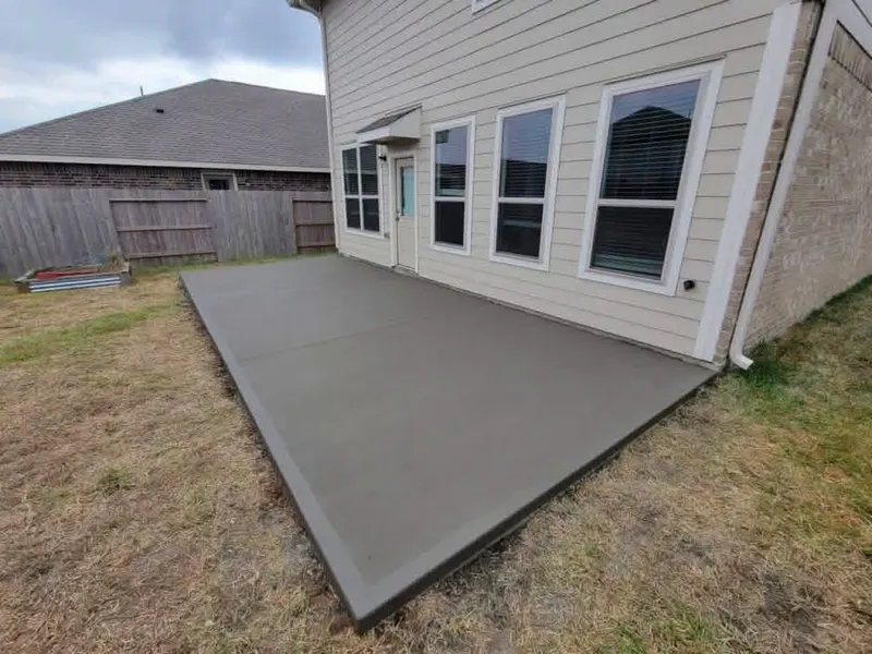 Concrete patio slab beside a two-story home with siding