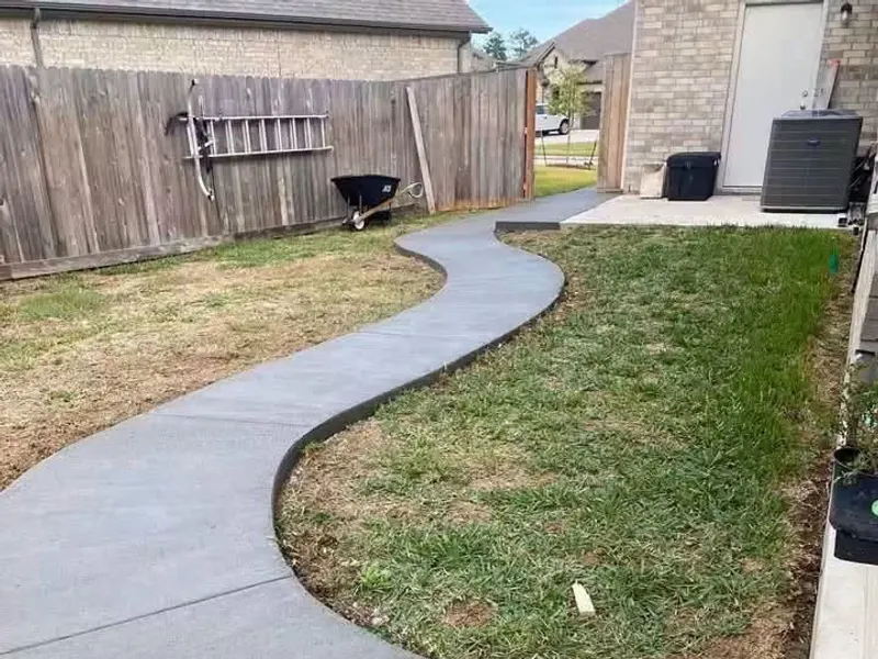 Curved concrete walkway through a backyard