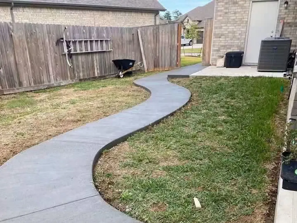 Curved concrete walkway through a backyard in the Houston area